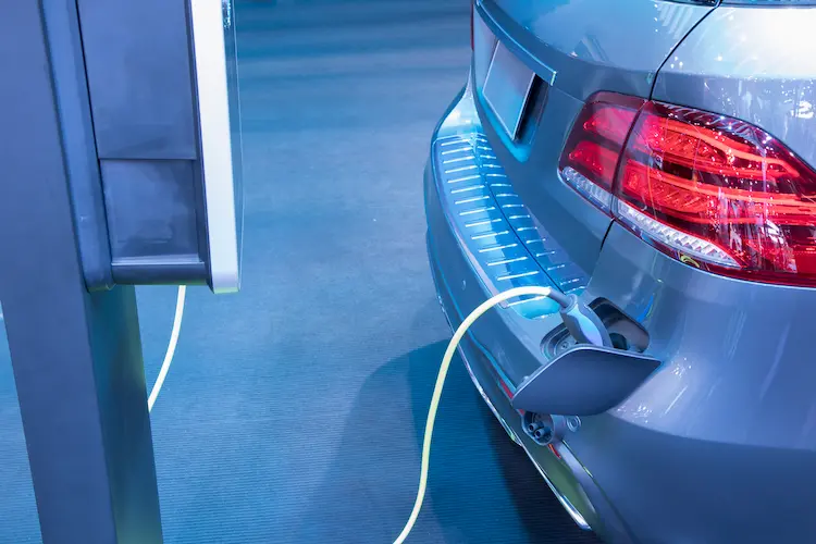 Srebrny samochód elektryczny podłączony do stacji ładowania – wizualizacja procesu transformacji floty na samochody elektryczne w polskich firmach