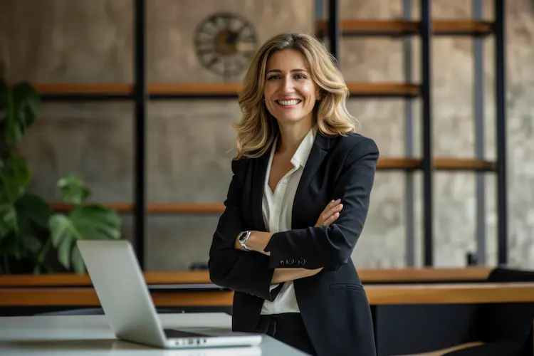 Uśmiechnięta kobieta sukcesu w czarnym żakiecie przy laptopie – ilustracja do finansowego portretu Polek.