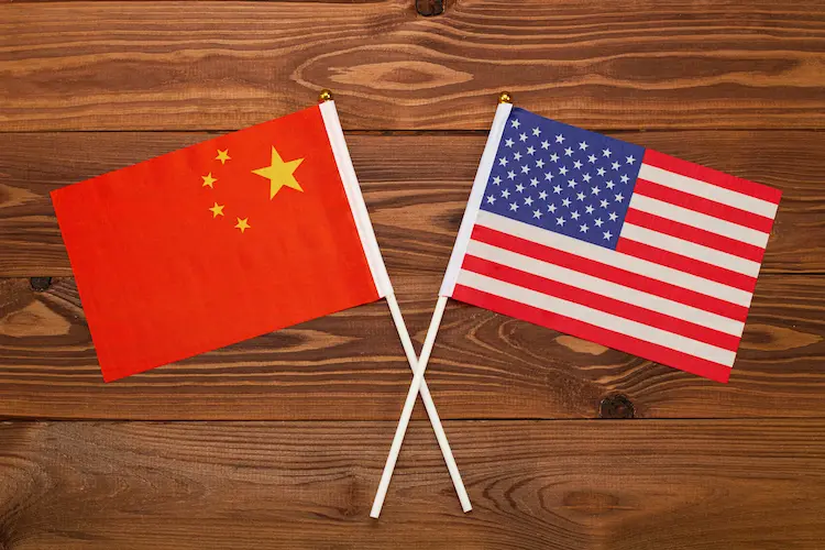 Skrzyżowane flagi Chin i USA na drewnianym tle – symbol wojny handlowej i sporów o cła w 2026 roku.