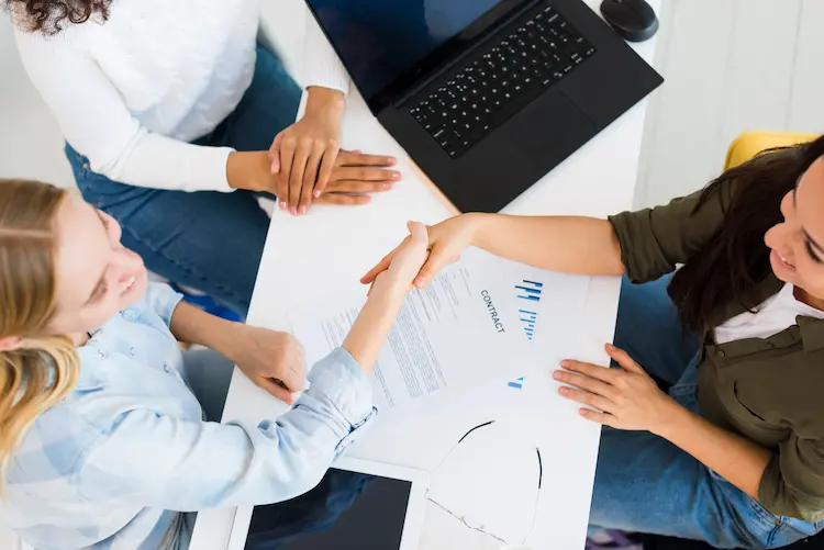 Uścisk dłoni nad umową o pracę – symbol pomyślnej rekrutacji i nowych możliwości na rynku pracy w 2026 roku.